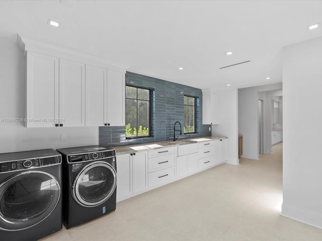 laundry area featuring washing machine and dryer, cabinets, light colored carpet, and sink