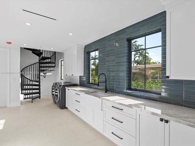 kitchen with washer and clothes dryer, sink, and white cabinets