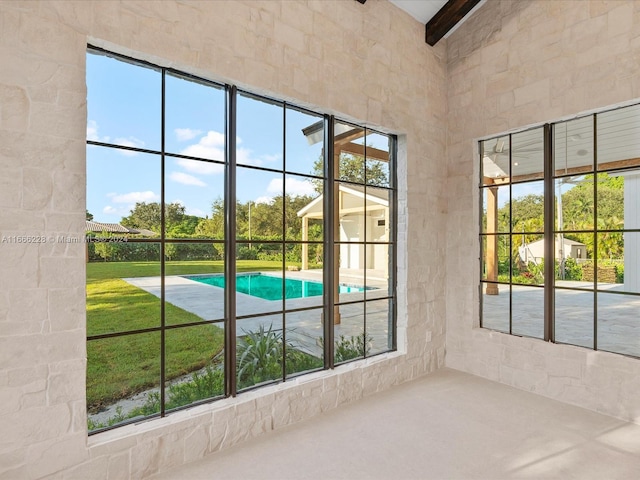 doorway to outside featuring a high ceiling, a wealth of natural light, and beam ceiling