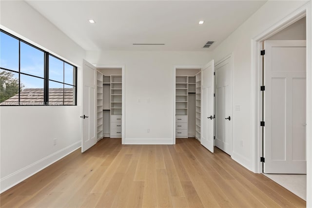 unfurnished bedroom featuring light hardwood / wood-style floors and a spacious closet