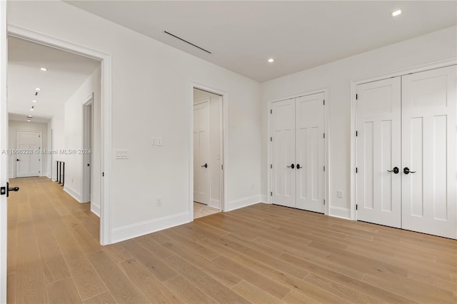 unfurnished bedroom with light wood-type flooring and two closets