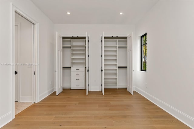 unfurnished bedroom featuring multiple closets and light hardwood / wood-style flooring