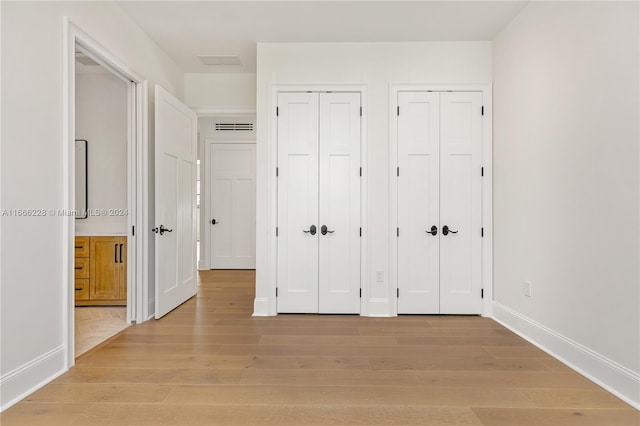 unfurnished bedroom featuring two closets and light hardwood / wood-style flooring