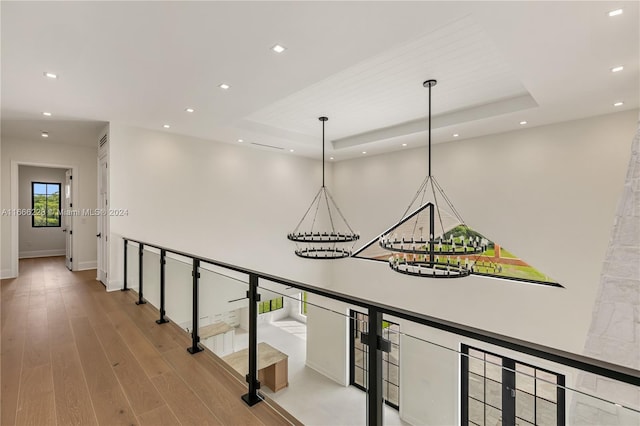 hallway with a raised ceiling and wood-type flooring