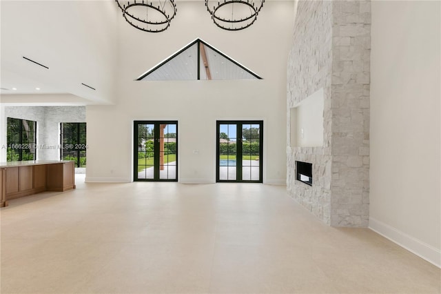 unfurnished living room with french doors, a fireplace, and a towering ceiling