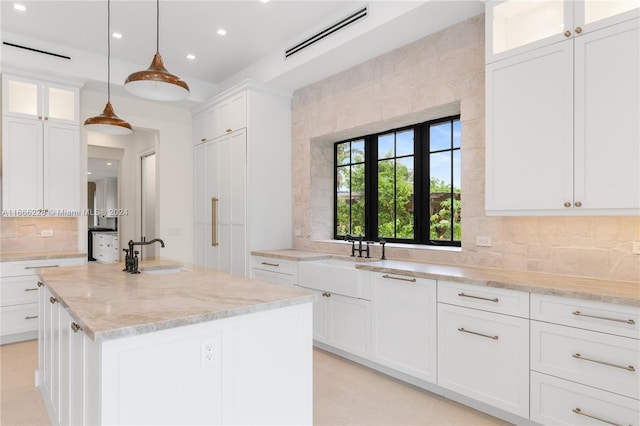 kitchen with a center island with sink, pendant lighting, white cabinetry, and sink