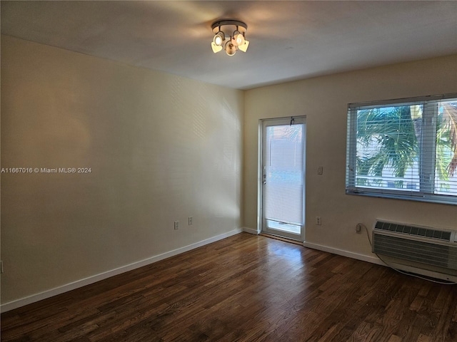 empty room with dark hardwood / wood-style floors and a wall mounted AC