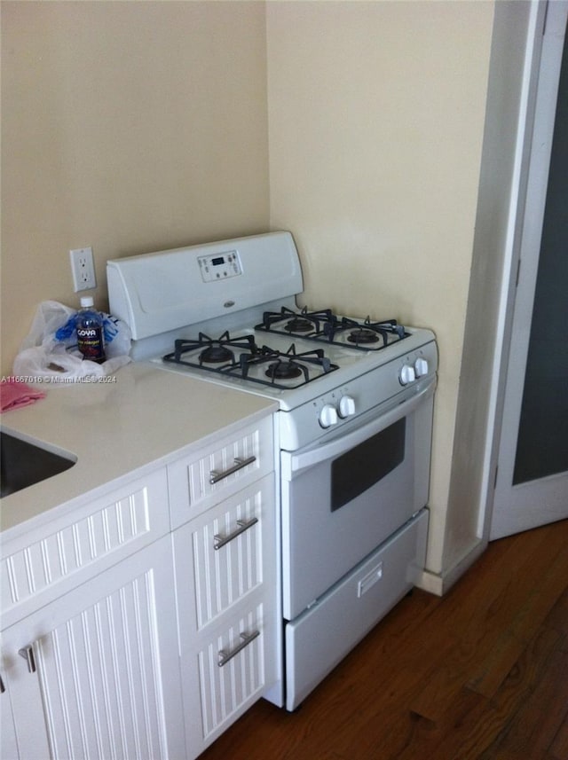 kitchen featuring white cabinets, dark wood-type flooring, and white gas range