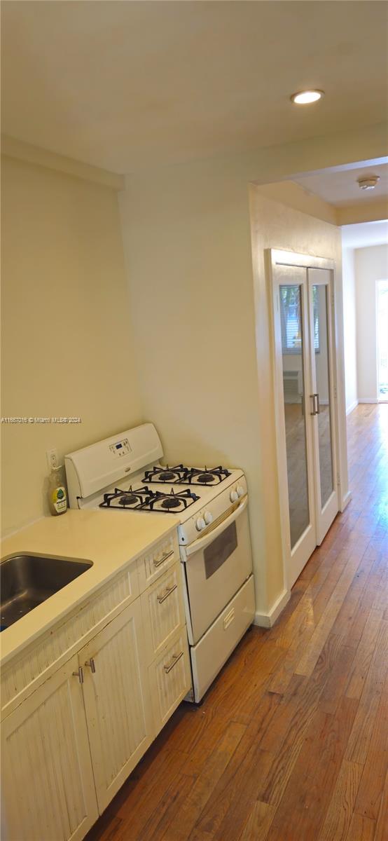 kitchen featuring hardwood / wood-style floors, white range with gas cooktop, and sink