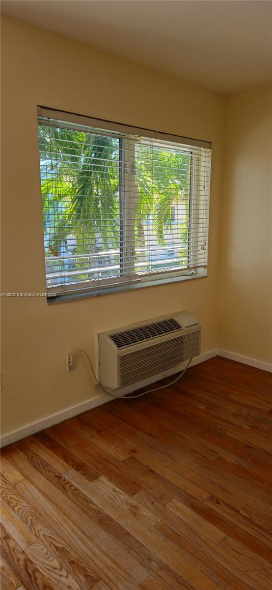 empty room with a wall unit AC and light hardwood / wood-style floors