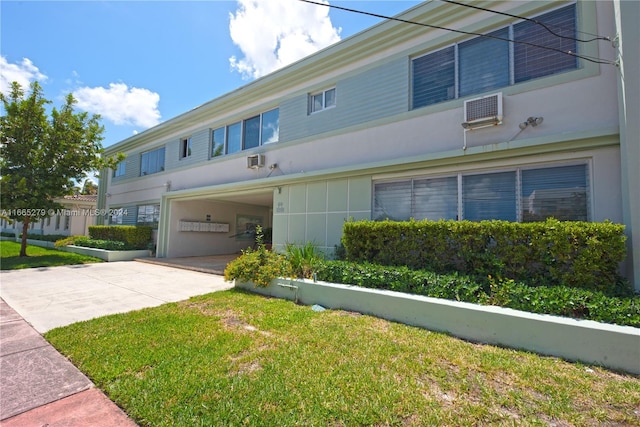 view of front of house with a garage, a front lawn, and a wall mounted AC