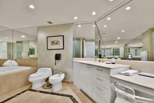 bathroom with vanity, toilet, tiled tub, a bidet, and tile patterned flooring