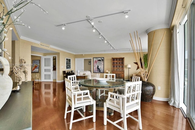 dining room with crown molding, dark wood-type flooring, and rail lighting