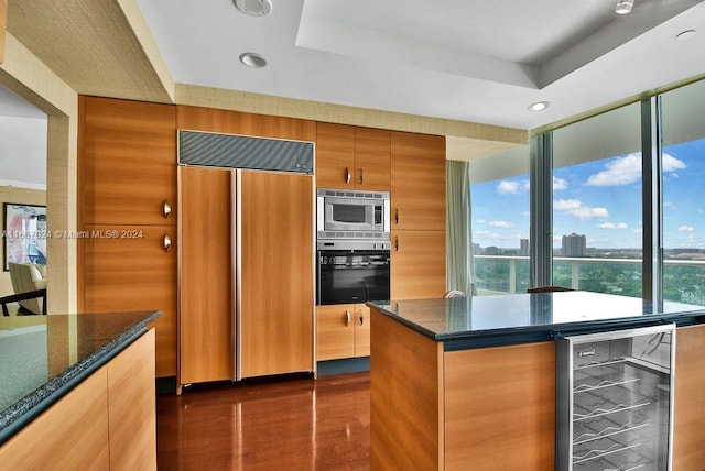 kitchen featuring built in appliances, a tray ceiling, beverage cooler, and dark wood-type flooring