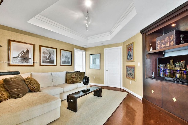 living area with baseboards, dark wood-type flooring, a raised ceiling, and crown molding