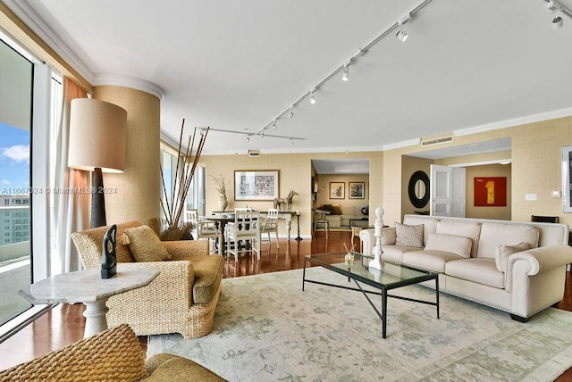 living room with track lighting, crown molding, wood finished floors, and visible vents