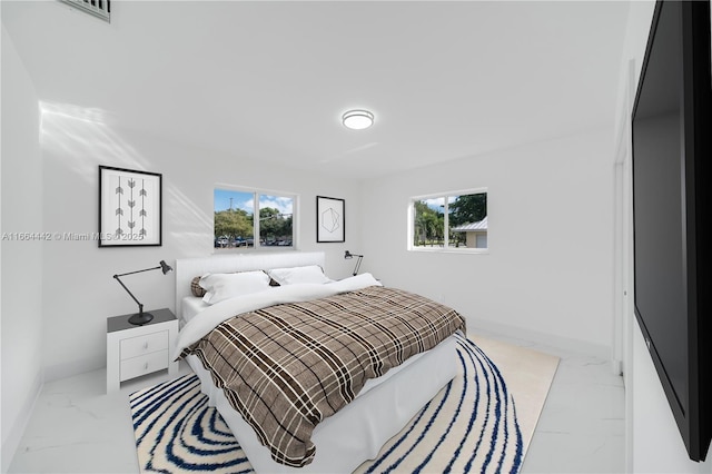 bedroom with marble finish floor, multiple windows, and baseboards