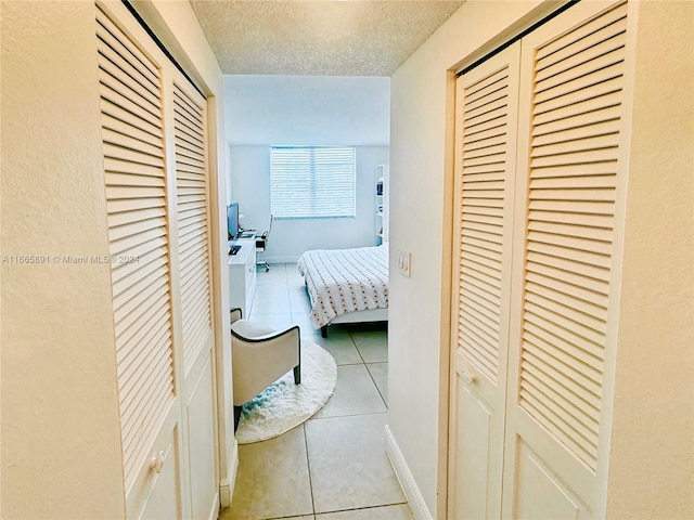 corridor with a textured ceiling and light tile patterned flooring