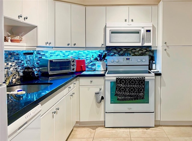 kitchen with decorative backsplash, light tile patterned floors, white appliances, and white cabinetry