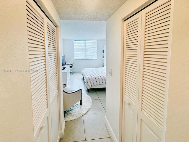 corridor featuring a textured ceiling and light tile patterned floors