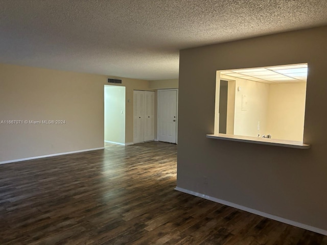 unfurnished room featuring a textured ceiling and dark hardwood / wood-style flooring