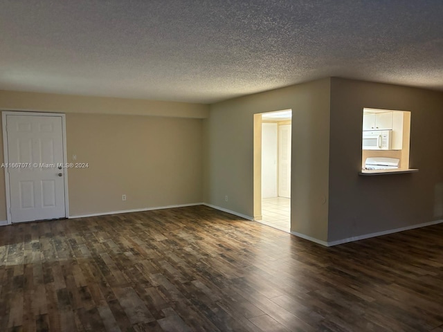 empty room featuring a textured ceiling and dark hardwood / wood-style floors