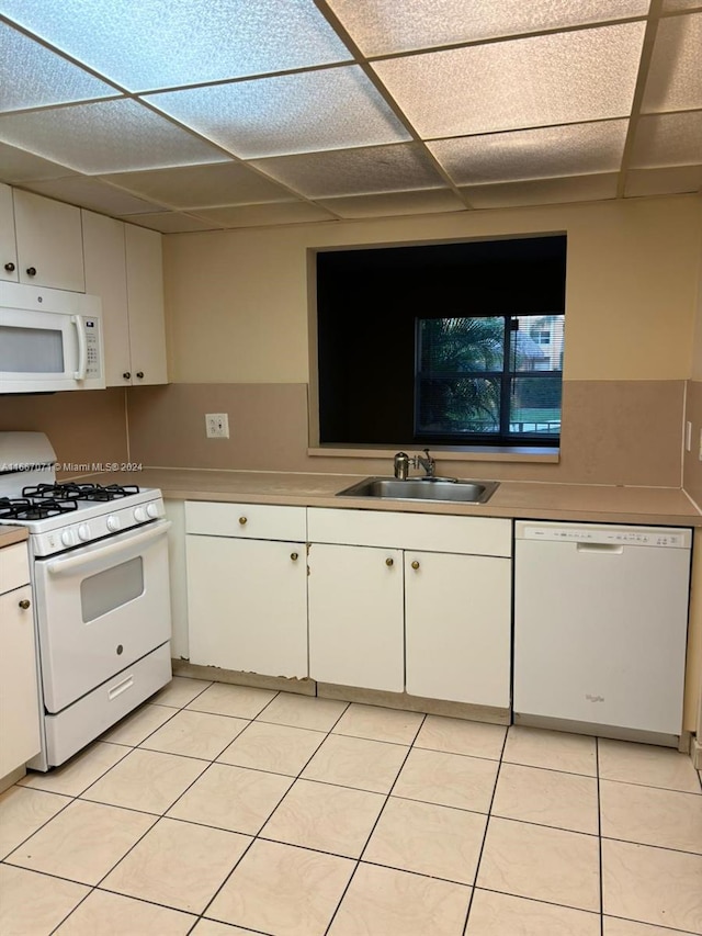 kitchen with white cabinetry, white appliances, light tile patterned floors, a drop ceiling, and sink