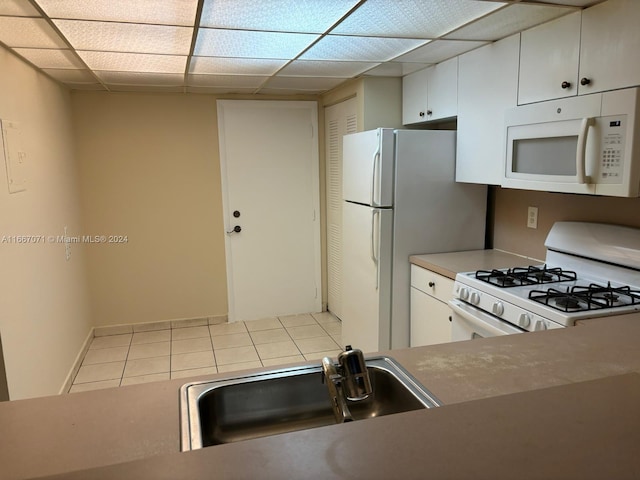 kitchen featuring a drop ceiling, sink, white appliances, and white cabinetry