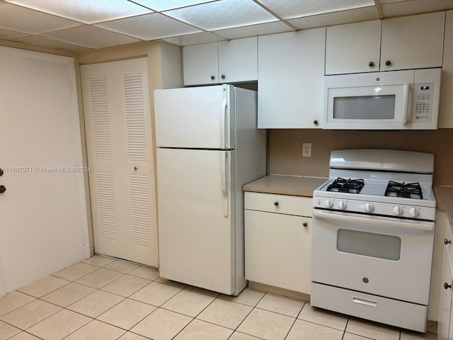 kitchen featuring white appliances, white cabinetry, light tile patterned floors, and a drop ceiling