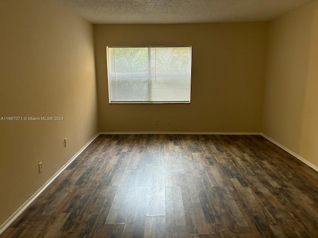 empty room with a textured ceiling and dark hardwood / wood-style flooring