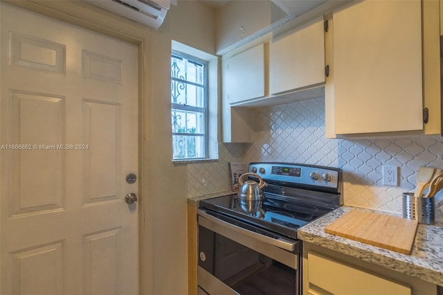 kitchen with light stone countertops, stainless steel range with electric stovetop, and tasteful backsplash