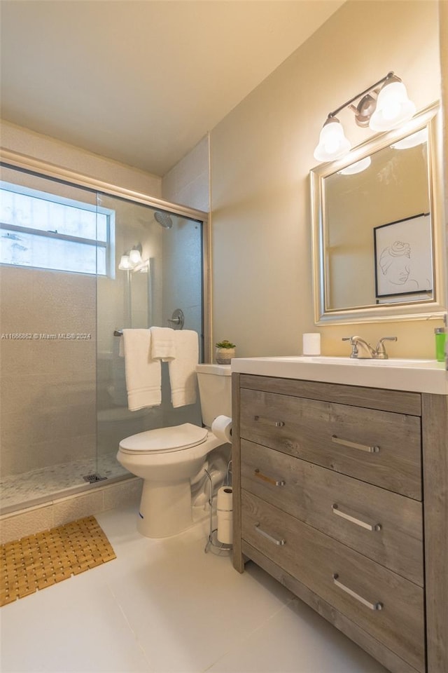 bathroom with vanity, toilet, a shower with door, and tile patterned floors