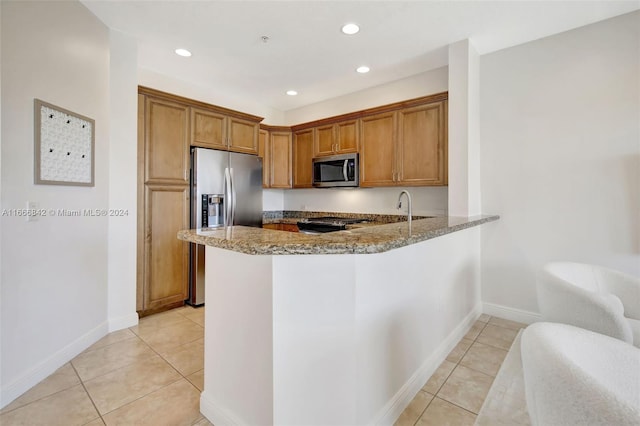 kitchen with light stone counters, kitchen peninsula, appliances with stainless steel finishes, and light tile patterned floors