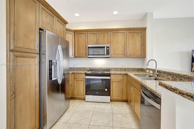 kitchen featuring light tile patterned floors, light stone countertops, appliances with stainless steel finishes, and sink