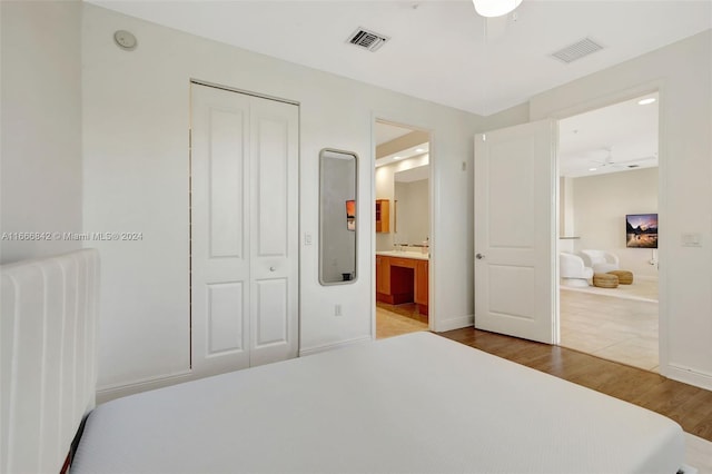 bedroom featuring wood-type flooring, a closet, connected bathroom, and radiator heating unit