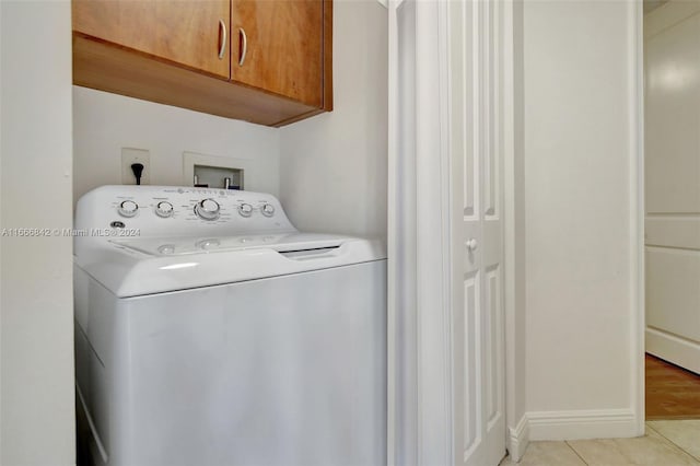 clothes washing area with washer / clothes dryer, cabinets, and light tile patterned floors