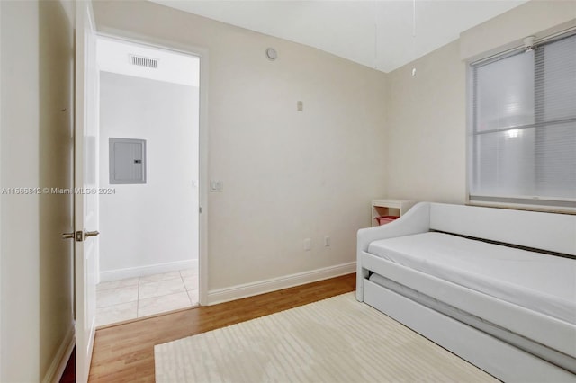 bedroom with electric panel and hardwood / wood-style floors