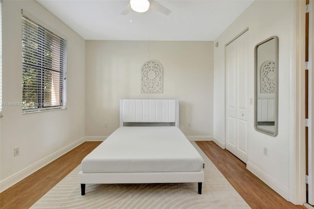 bedroom with light hardwood / wood-style floors, ceiling fan, and a closet