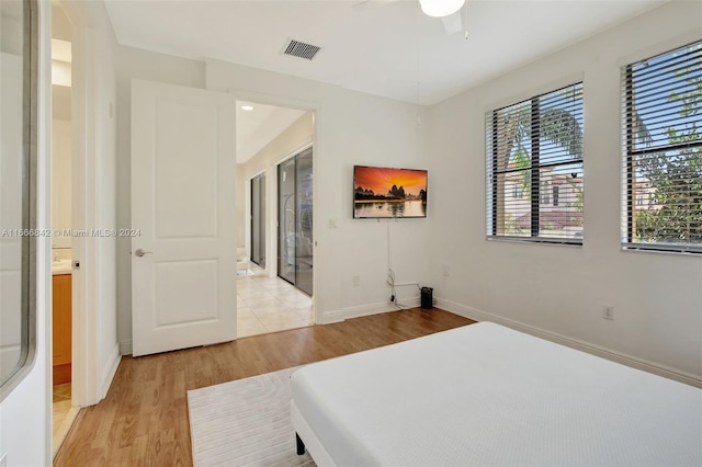 bedroom featuring light wood-type flooring, ensuite bath, and ceiling fan