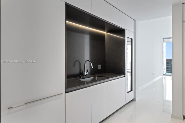 interior space featuring white cabinets, sink, and tasteful backsplash