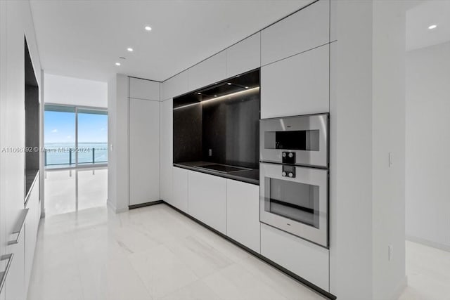 kitchen featuring expansive windows, white cabinets, and a water view