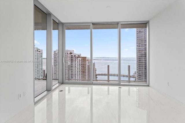 empty room with a wealth of natural light, a water view, and a wall of windows