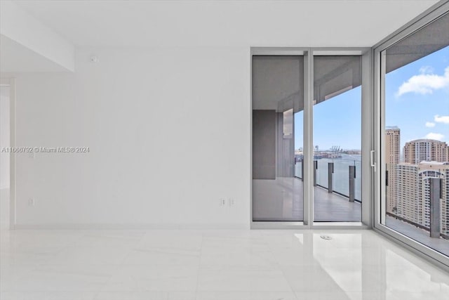 unfurnished room with light tile patterned flooring and a wall of windows