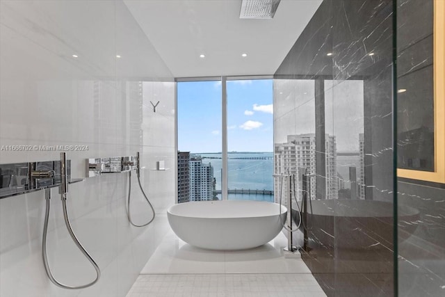 bathroom with a wall of windows, shower with separate bathtub, a water view, and tile patterned flooring