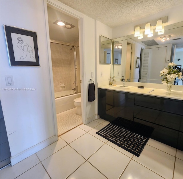 full bathroom featuring tile patterned flooring, a textured ceiling, enclosed tub / shower combo, vanity, and toilet