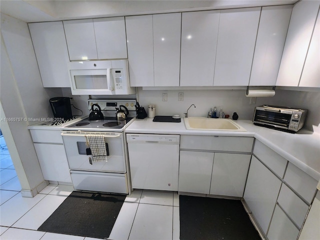 kitchen with light tile patterned floors, white cabinets, sink, and white appliances