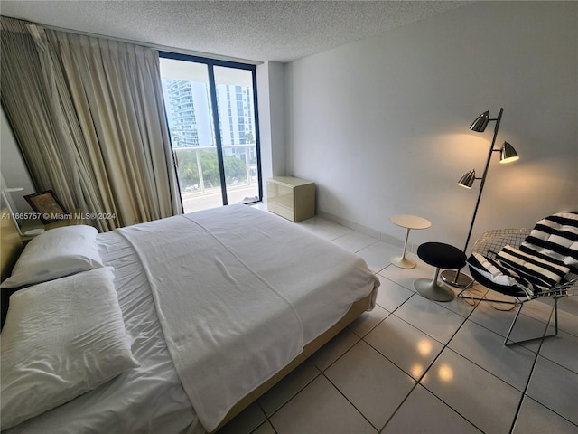 tiled bedroom with a textured ceiling, access to outside, and floor to ceiling windows