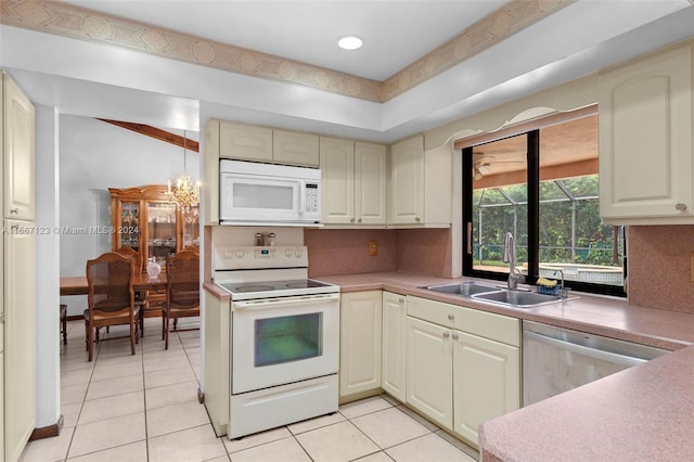 kitchen featuring a chandelier, light tile patterned flooring, sink, white appliances, and cream cabinets