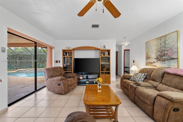 living room with ceiling fan, a textured ceiling, and light tile patterned floors