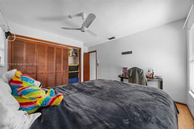 bedroom featuring a closet, ceiling fan, hardwood / wood-style flooring, and a textured ceiling